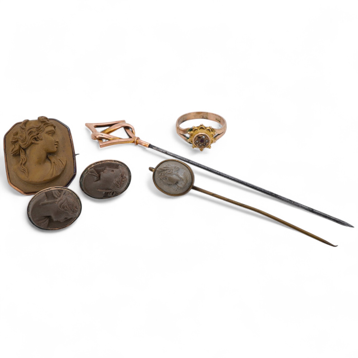 A collection of jewellery, comprising: a brooch, pair of earrings and a stick pin set with lava cameos; a stick pin capped with a geometric motif in gold, stamped 9CT; and a ring set with seed pearls and a garnet